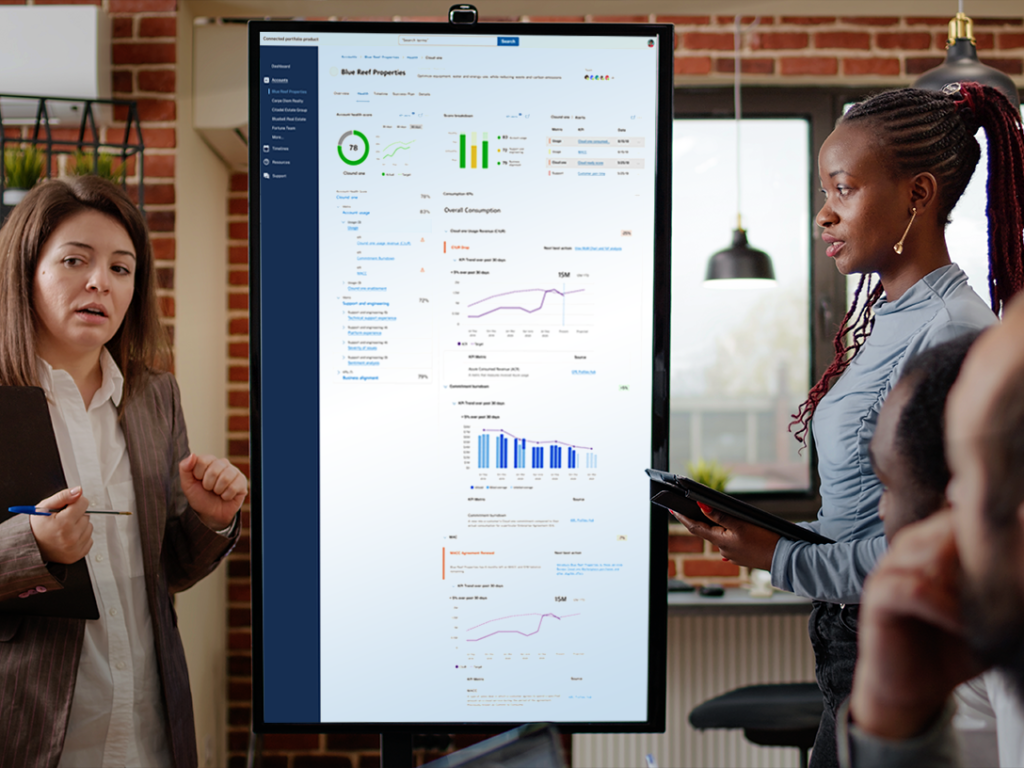 A diverse group of colleagues reviewing a large vertical digital display showing charts and graphs during a business meeting in a modern office.